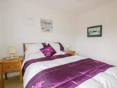a bedroom with a bed with a purple blanket on it at Brambles in Gorran Haven