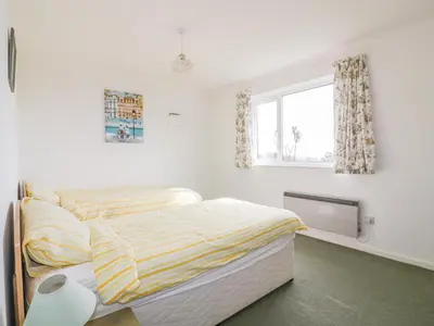 a white bedroom with a bed and a window at Brambles in Gorran Haven