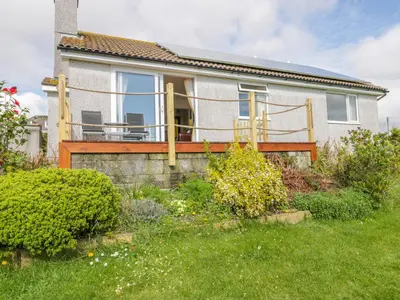 a house with a deck in the yard at Brambles in Gorran Haven