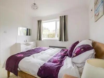 a bedroom with a bed with a purple blanket at Brambles in Gorran Haven