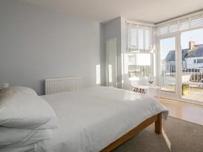 a white bedroom with a bed and a large window at Chy-an-Brae in Newquay