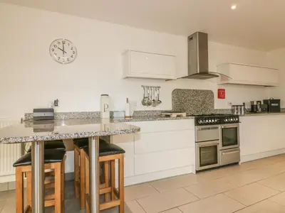 a kitchen with white cabinets and a clock on the wall at Chy-an-Brae in Newquay