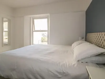a bedroom with a white bed with a window at Chy-an-Brae in Newquay