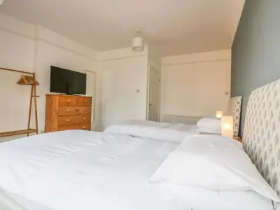 two beds in a bedroom with a tv and a dresser at Chy-an-Brae in Newquay