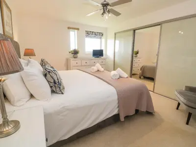 a bedroom with a large white bed with a fan at Ocean Seven in Newquay