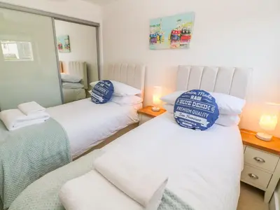 two twin beds in a room with a mirror at Ocean Seven in Newquay