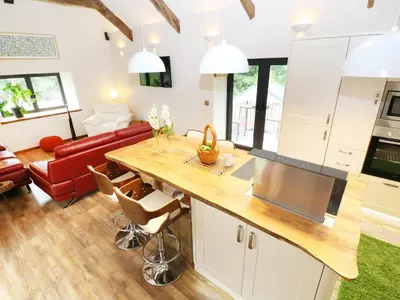 a kitchen and living room with a table and a couch at The Cart House in Liskeard