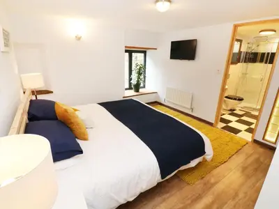 a bedroom with a large white bed and a television at The Cart House in Liskeard