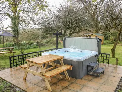 a hot tub with a picnic table and a bench at The Cart House in Liskeard