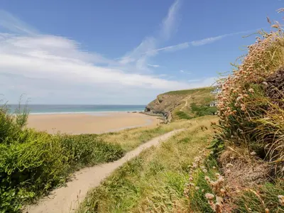 a dirt path leading to a beach with the ocean at Little May in Newquay