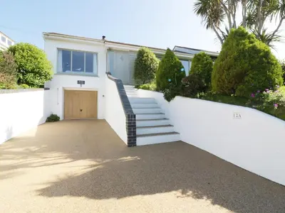 a white house with stairs leading to a door at Keelyn in Crantock