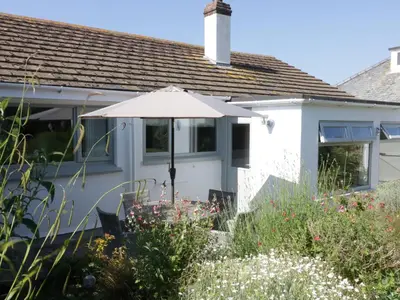 a white house with an umbrella in the garden at Keelyn in Crantock