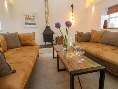 a living room with couches and a table with wine glasses at Silvermine House in St Austell