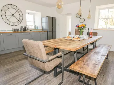 a kitchen with a wooden table and chairs at Silvermine House in St Austell