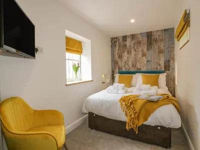 a bedroom with a bed and a chair at Silvermine House in St Austell