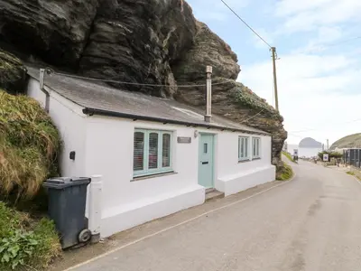 a cottage on a road next to a mountain at Smugglers Cottage in Tintagel