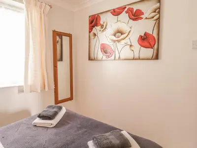 a bedroom with a picture of flowers on the wall at Ducks Ditty in Liskeard