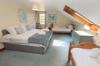 a bedroom with two twin beds and a staircase at Beggars Roost in Truro