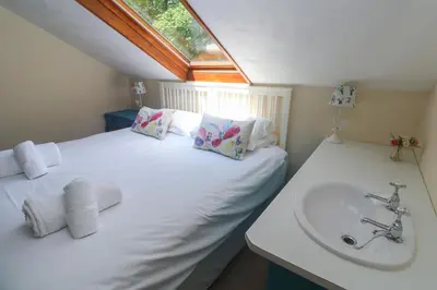 a white bed with a sink and a window at Beggars Roost in Truro