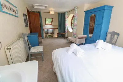 a bedroom with two beds with blue cabinets and chairs at Beggars Roost in Truro