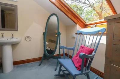 a bathroom with a mirror and a chair and a sink at Beggars Roost in Truro