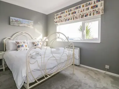 a bedroom with a white bed and a window at Bayview in St Austell