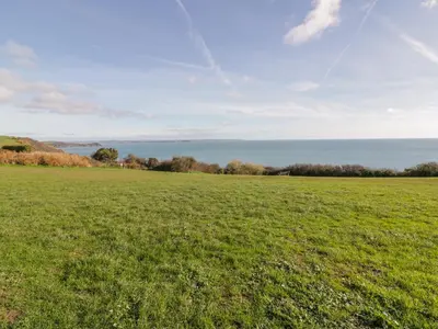 a field of grass with the ocean in the background at Bayview in St Austell