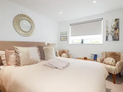 a bedroom with a bed with a mirror and a chair at Apartment no 21 in Newquay