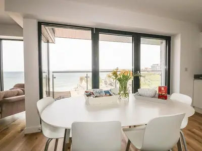 a white dining room with a white table and chairs at Onshore 7 in Newquay