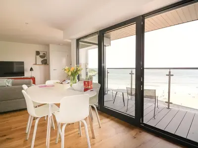 a dining room with a table and chairs with a view of the beach at Onshore 7 in Newquay