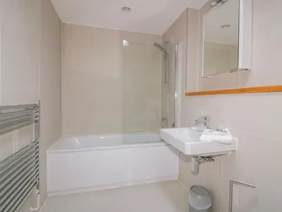a white bathroom with a sink and a tub and a toilet at Onshore 7 in Newquay