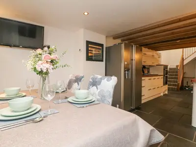 a dining room table with a vase of flowers on it at Miner's Rest in Camborne