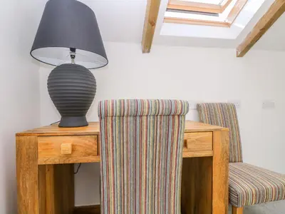 a lamp sitting on a table next to a chair at Miner's Rest in Camborne