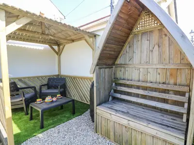a large wooden shed with a table and a bench at Miner's Rest in Camborne