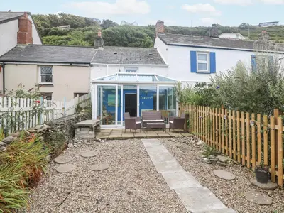 a white house with a conservatory in front of it at Pebble Cottage in Redruth