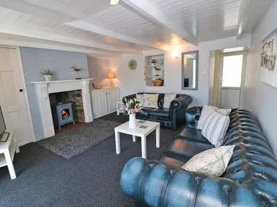 a living room with a leather couch and a fireplace at Pebble Cottage in Redruth