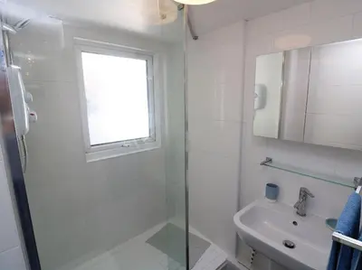 a white bathroom with a shower and a sink at Pebble Cottage in Redruth