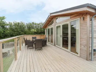 a wooden deck with a table and chairs on it at 3 Valley View in Looe