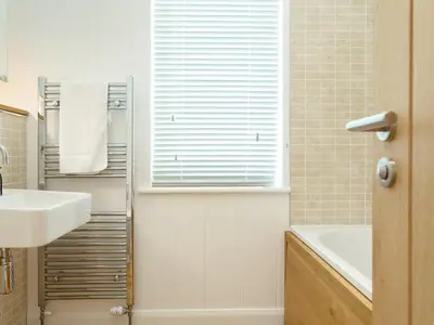 a bathroom with a sink and a tub and a window at 3 Valley View in Looe
