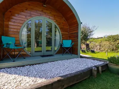 a wooden cabin with two chairs and a patio at The Lamb Shack in Bodmin