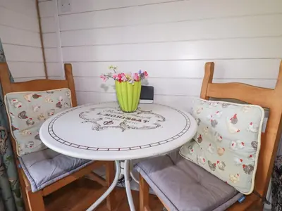 a table with two chairs and a vase of flowers on it at The Lamb Shack in Bodmin