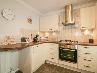 a kitchen with white cabinets and a clock on the wall at Dune Haven in Truro
