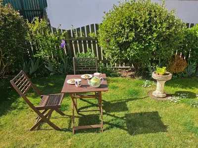 a wooden table and chair in a yard at Chiffchaff in Padstow