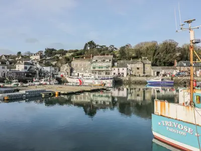 a boat docked in a marina with a town at Chiffchaff in Padstow