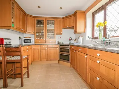 a large kitchen with wooden cabinets and a sink at Chiffchaff in Padstow