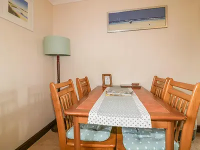 a dining room table with four chairs and a lamp at Chiffchaff in Padstow
