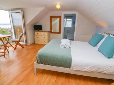 a bedroom with a large bed with blue pillows at Mount View Cottage in Marazion