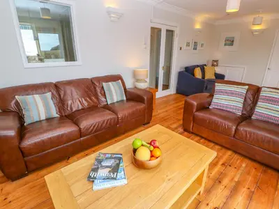a living room with two brown leather couches and a table at Mount View Cottage in Marazion