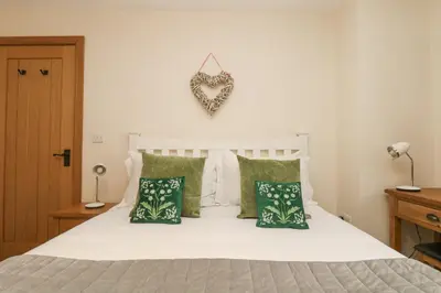 a bedroom with a white bed with green pillows at The Lily Pad in Camborne