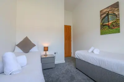 a bedroom with two beds and a lamp on a table at Sea Breeze 17 Gannel in Truro